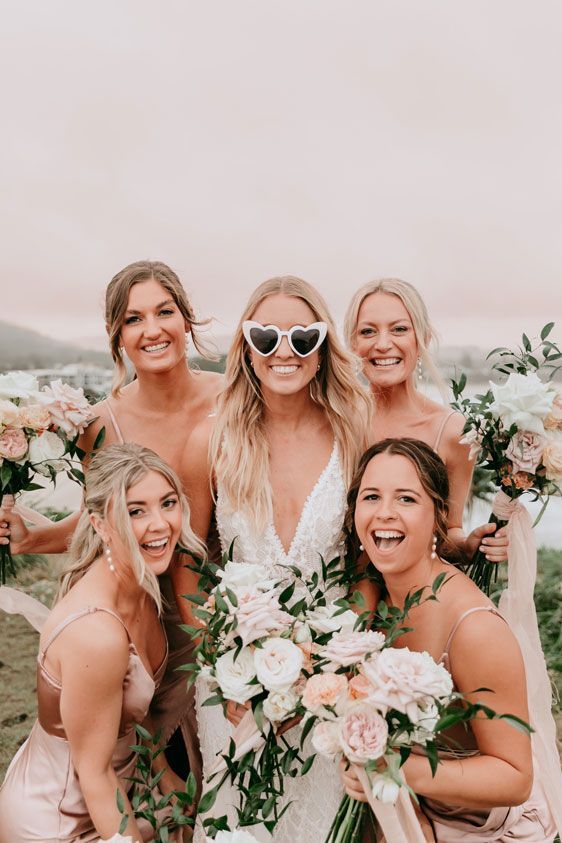 A bride and her bridesmaids are posing for a picture together.