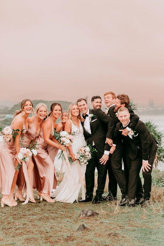 The bride and groom are posing for a picture with their wedding party.