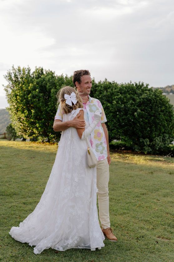 A bride and groom are standing next to each other in a grassy field.