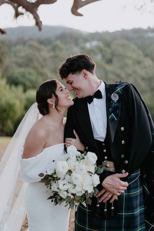 A bride and groom are standing next to each other and looking at each other.