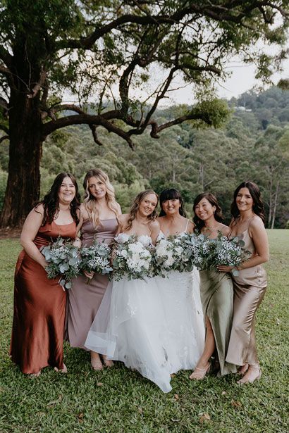 A bride and her bridesmaids are posing for a picture in a field.