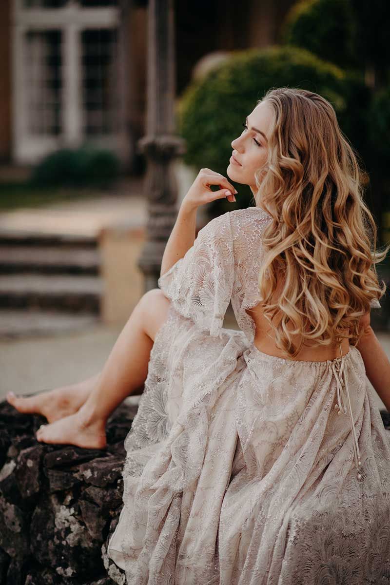 A woman in a white dress is sitting on a rock.