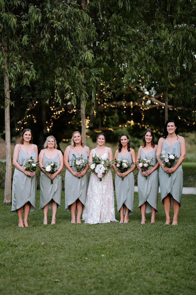 A bride and her bridesmaids are posing for a picture in a field.