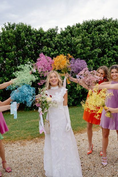 A bride and her bridesmaids are holding colorful bouquets of flowers.