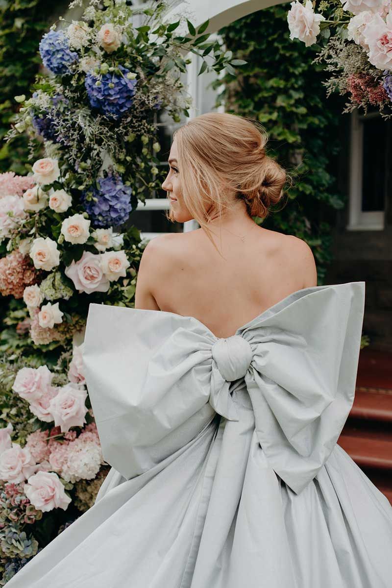 A woman in a wedding dress with a large bow on the back.