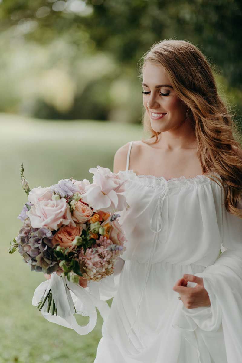A woman in a white dress is holding a bouquet of flowers.