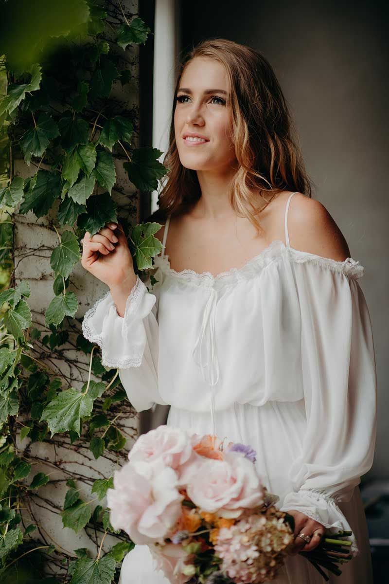 A woman in a white dress is holding a bouquet of flowers.