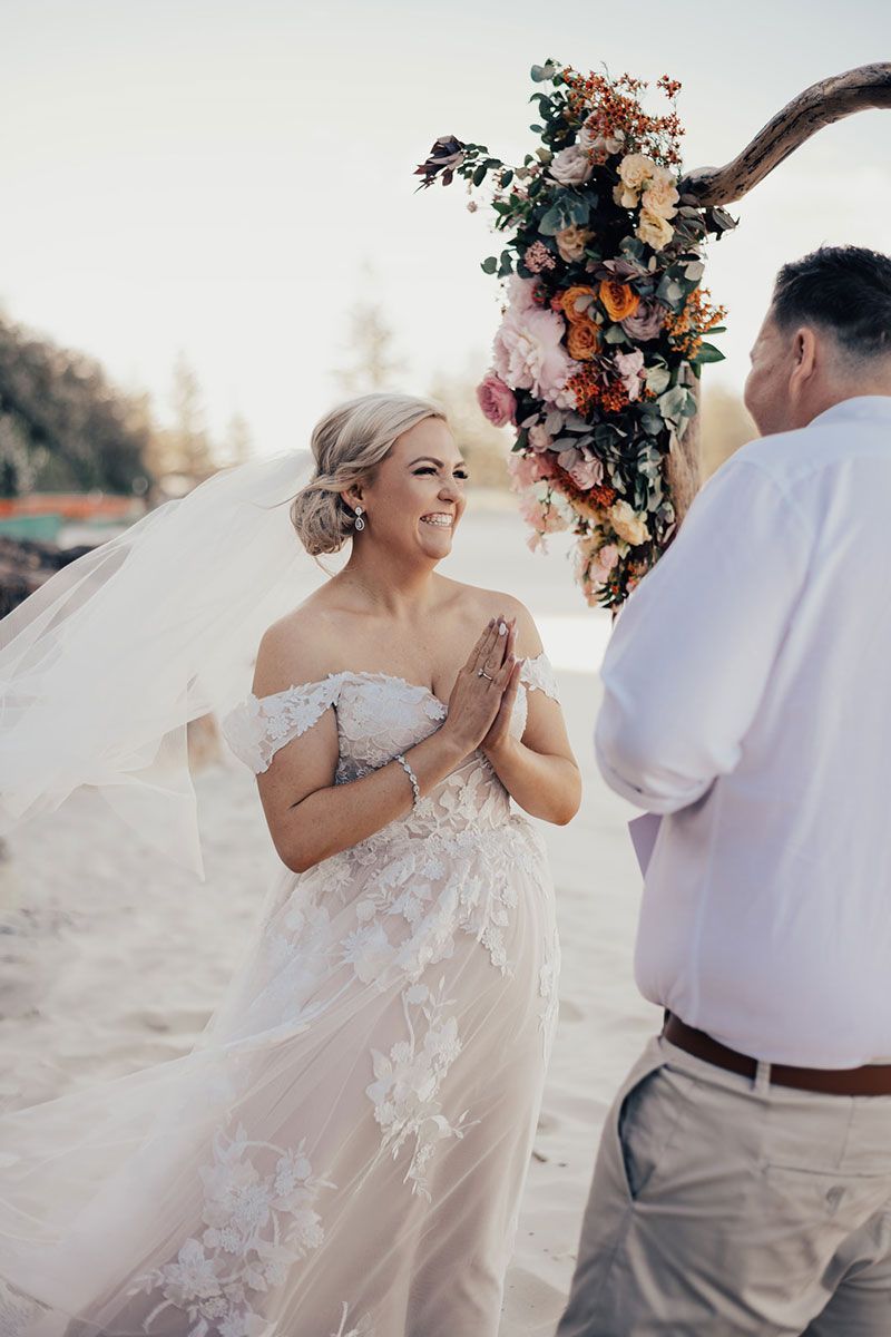 A bride and groom are standing next to each other on the beach.