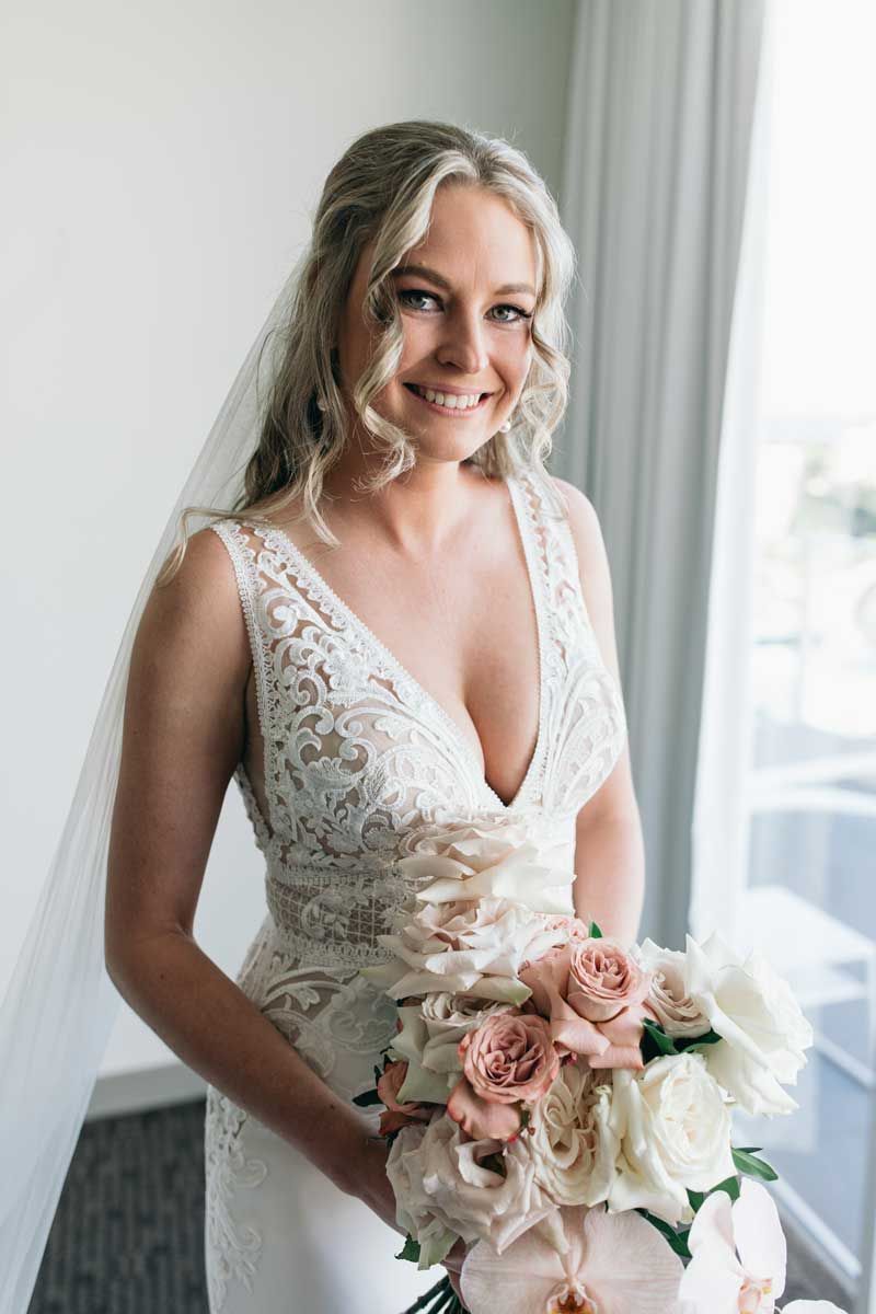 The bride is wearing a wedding dress and holding a bouquet of flowers.