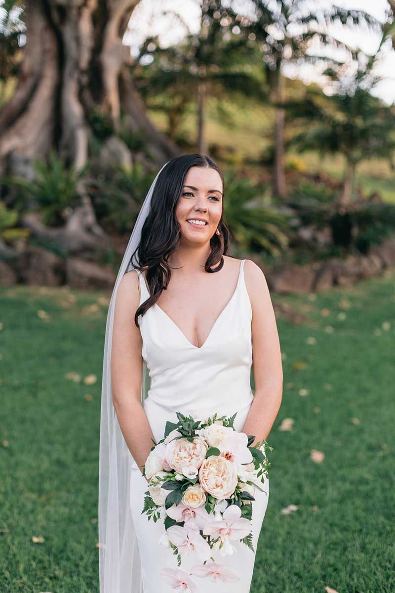 A bride in a white dress and veil is holding a bouquet of flowers.