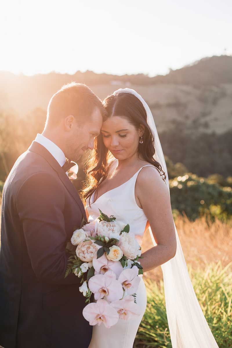 A bride and groom are posing for a picture in a field.