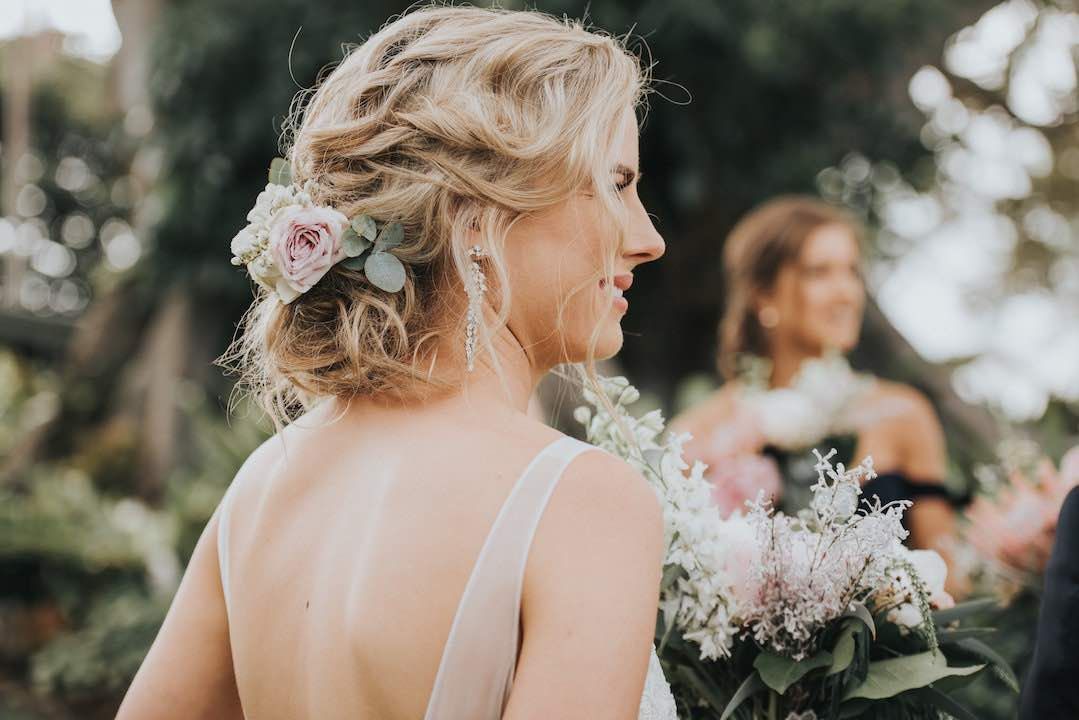 A bride in a wedding dress is holding a bouquet of flowers in her hair.