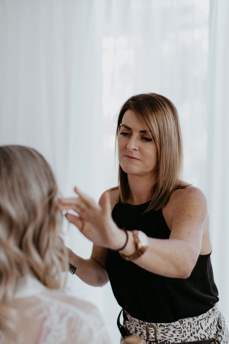 A woman is getting her hair done by a hairdresser in front of a mirror.