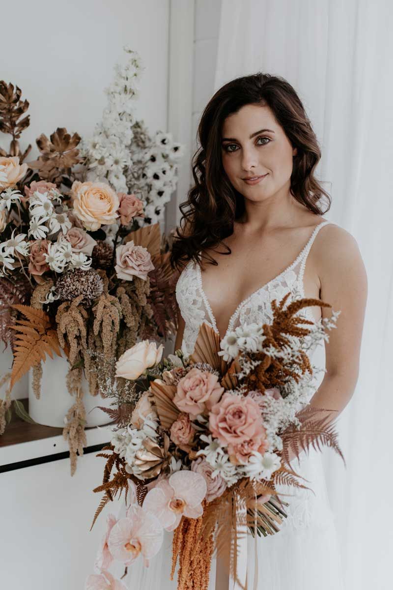 A woman in a white dress is holding a bouquet of flowers.