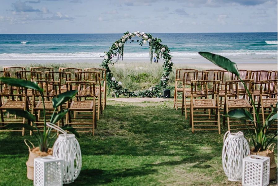 A bride and groom are posing for a picture on the beach.