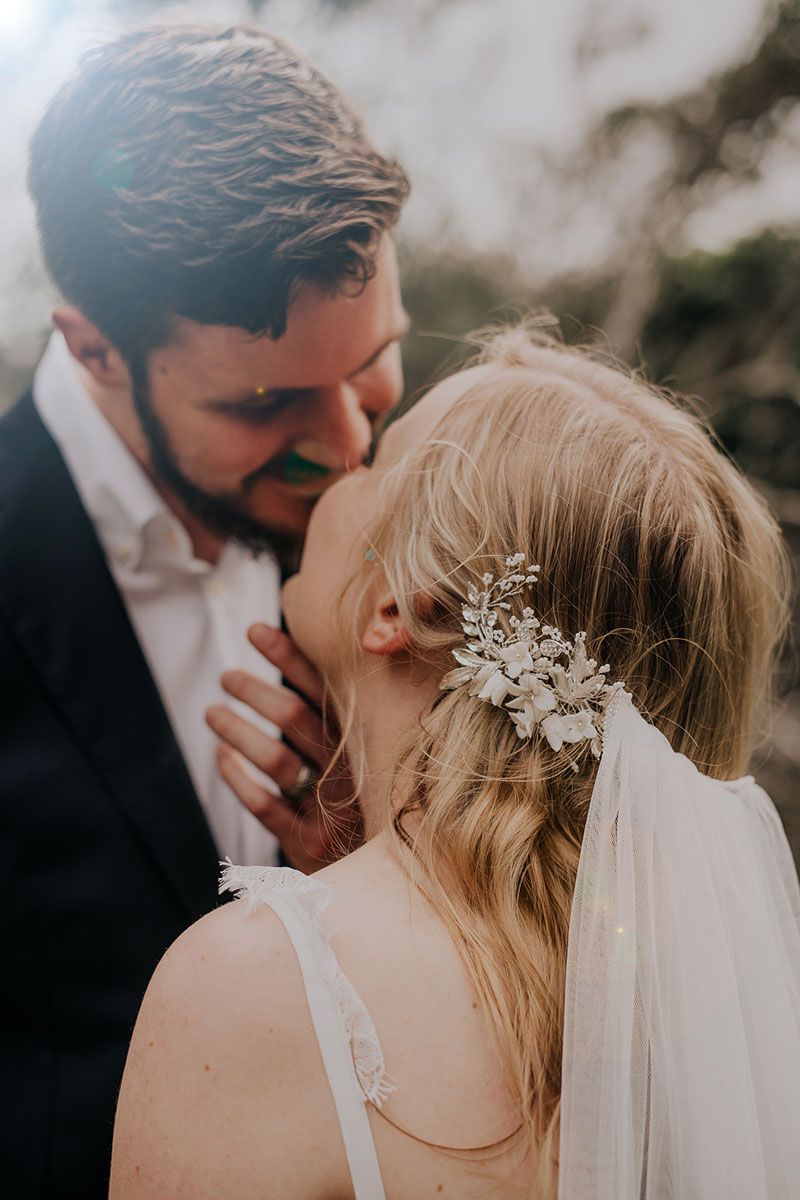 A bride and groom are kissing and the bride is wearing a veil.