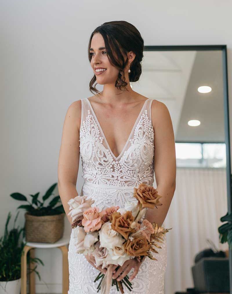 A woman in a wedding dress is holding a bouquet of flowers in front of a mirror.
