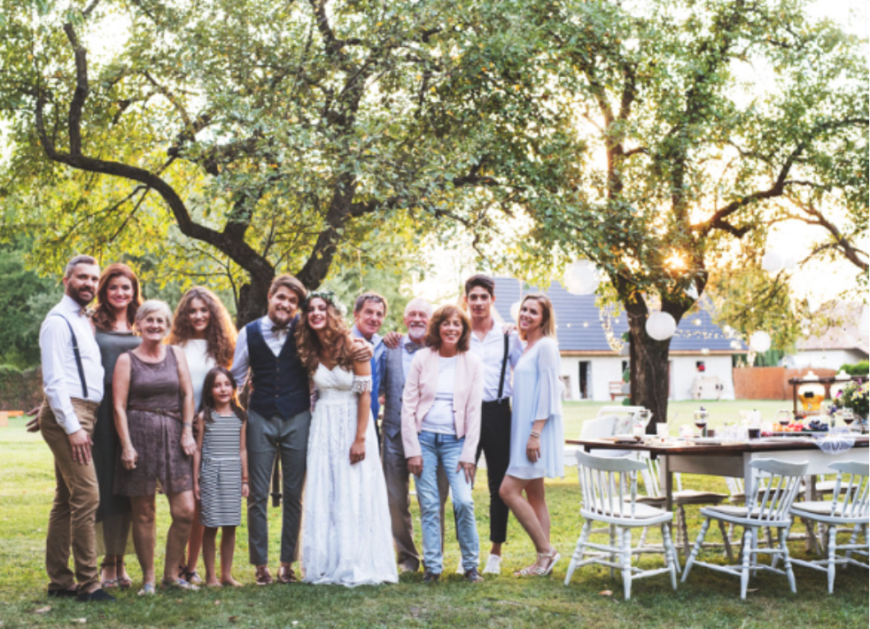 A bride and groom are posing for a picture with their family at their wedding reception.