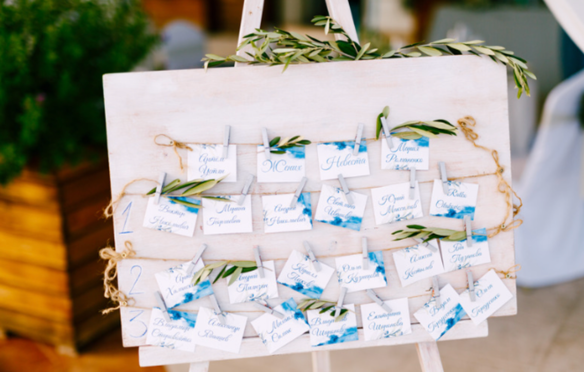 A wooden easel filled with seating cards for a wedding.