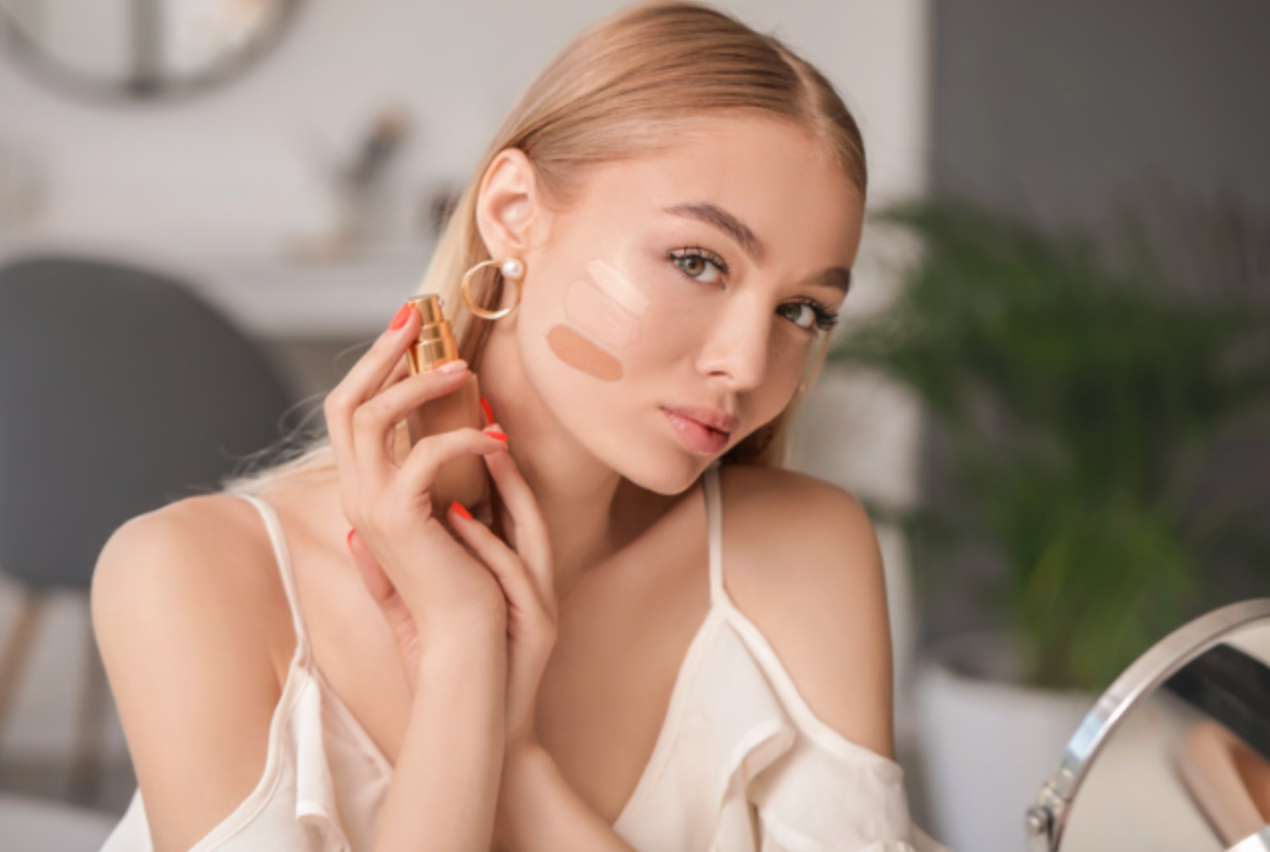 A woman is applying foundation to her face in front of a mirror.