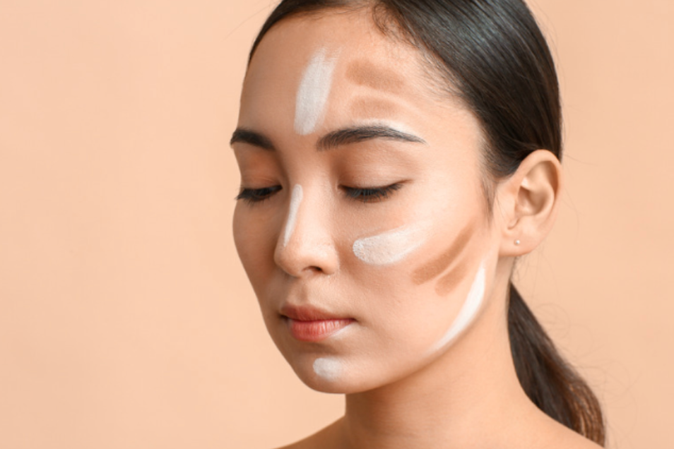 A woman is applying foundation to her face.