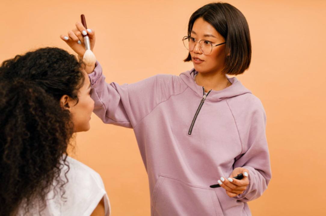 A woman is applying makeup to another woman 's face.