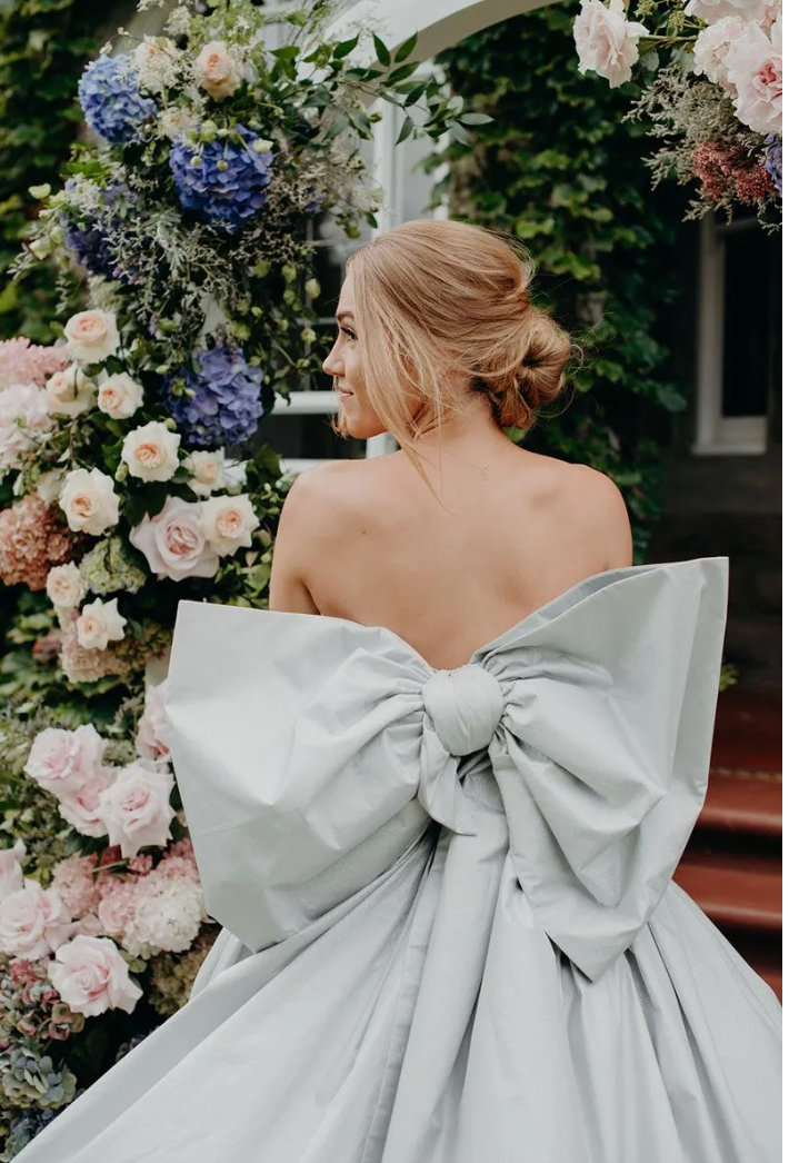 A woman in a wedding dress with a large bow on the back.