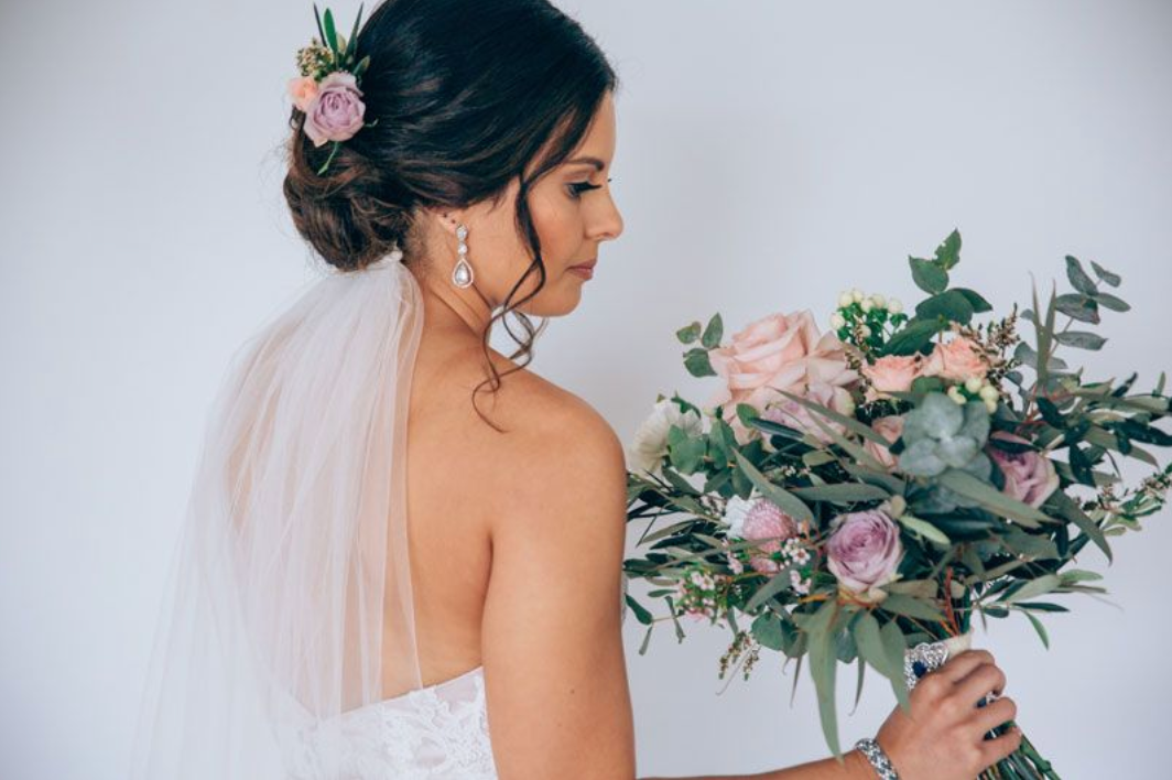 The bride is wearing a veil and holding a bouquet of flowers.