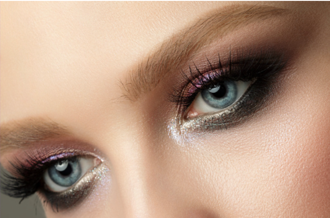 A close up of a woman 's blue eyes with smokey eye makeup.