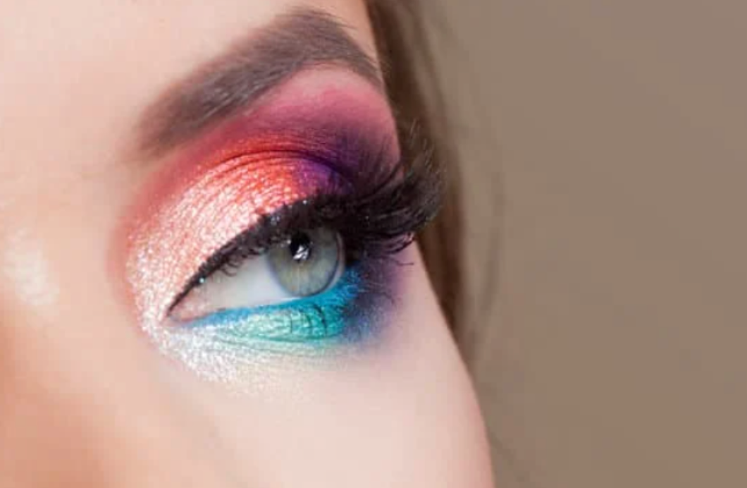 A close up of a woman 's eye with colorful eye makeup.