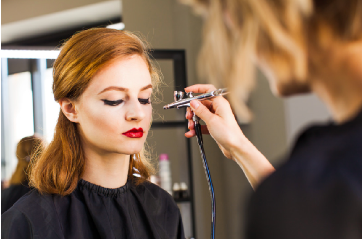 A woman is getting her makeup done by a makeup artist in a salon.