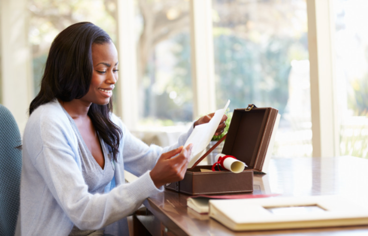 A woman is sitting at a desk looking at a piece of paper.