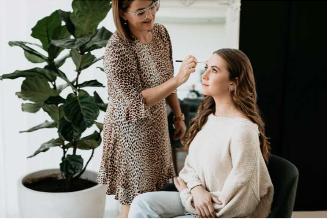 A woman is applying makeup to another woman 's face.