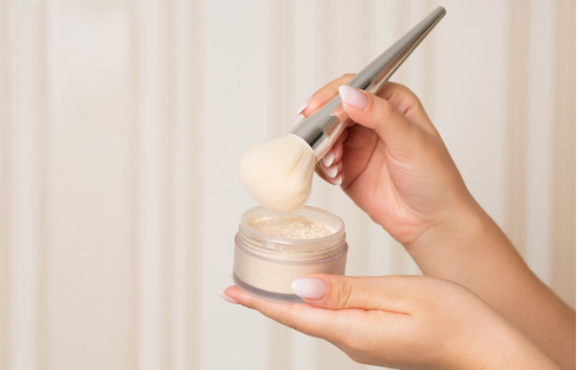 A woman is holding a jar of powder and a brush.