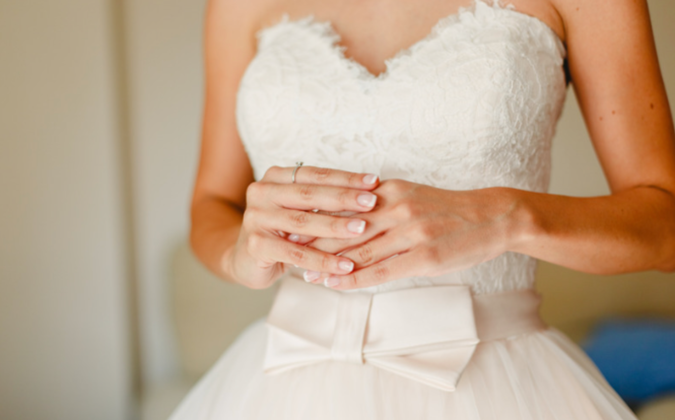 A woman in a wedding dress is holding her hands together.