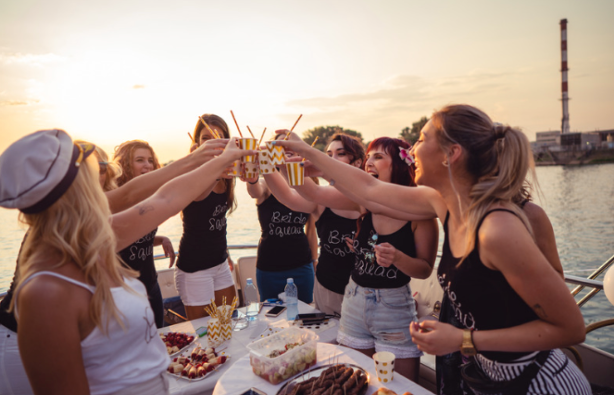 A group of women are toasting with drinks on a boat.