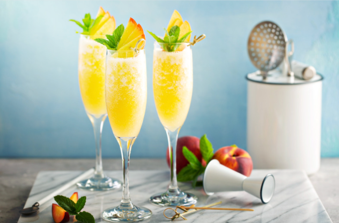 Three champagne flutes filled with a yellow drink on a table.