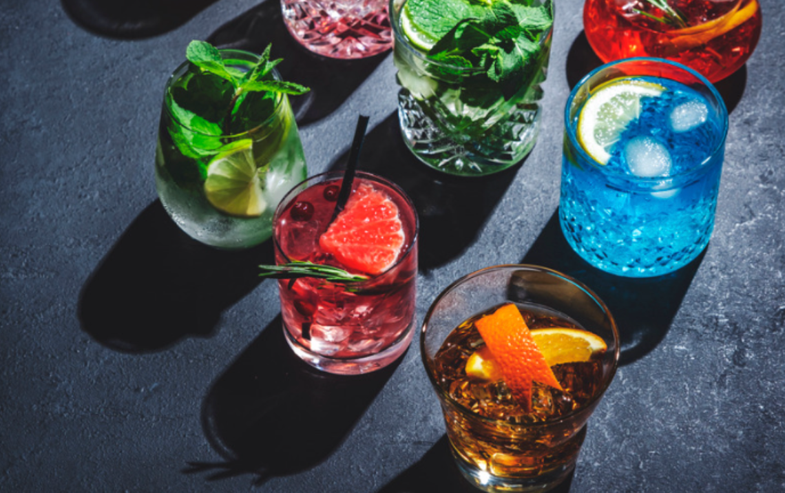 A variety of colorful cocktails are sitting on a table.