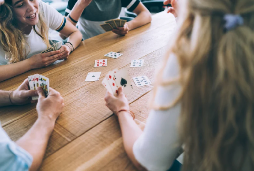 A group of people are sitting at a table playing cards.