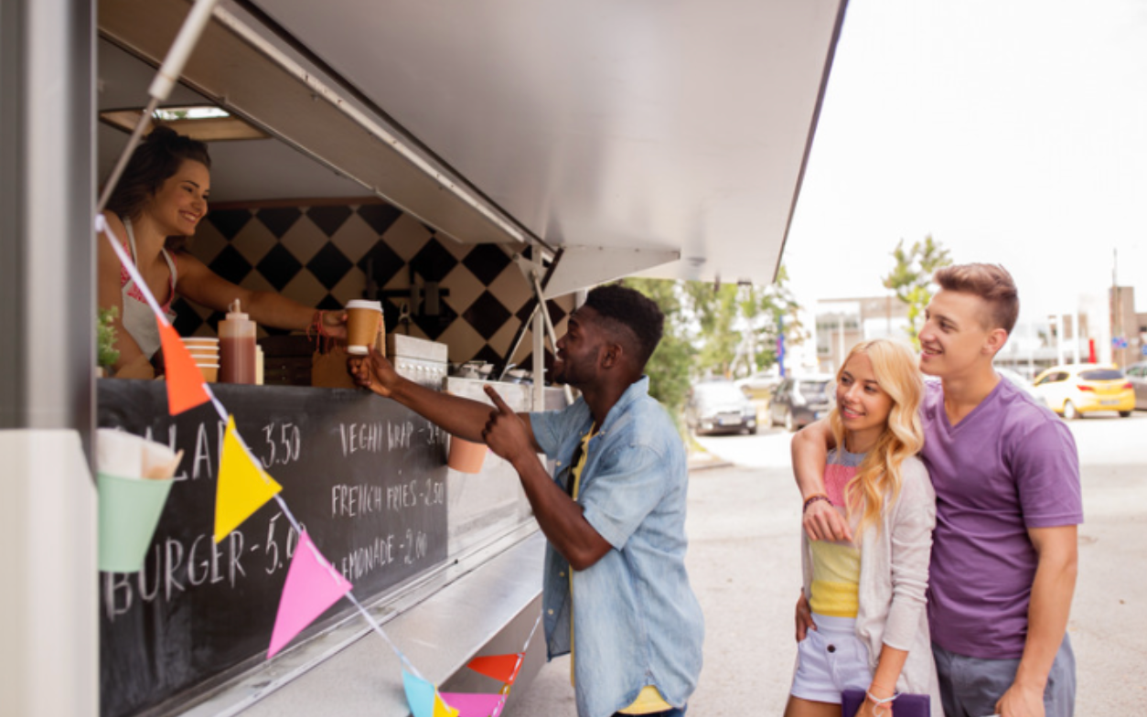 A group of people are standing in front of a food truck.