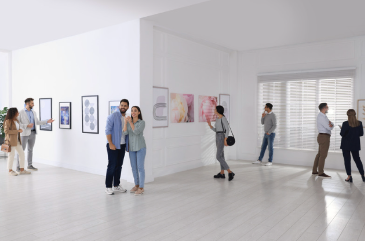 A group of people are looking at paintings in a museum.