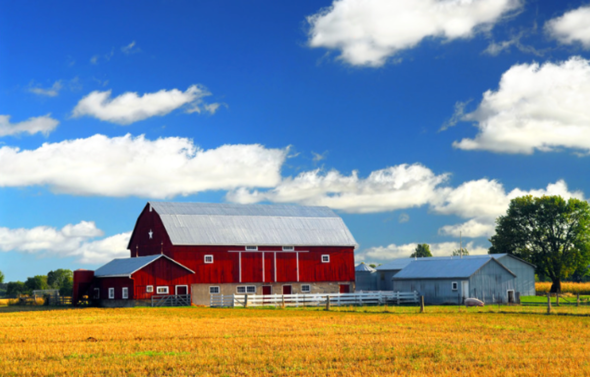 A red barn sits in the middle of a field