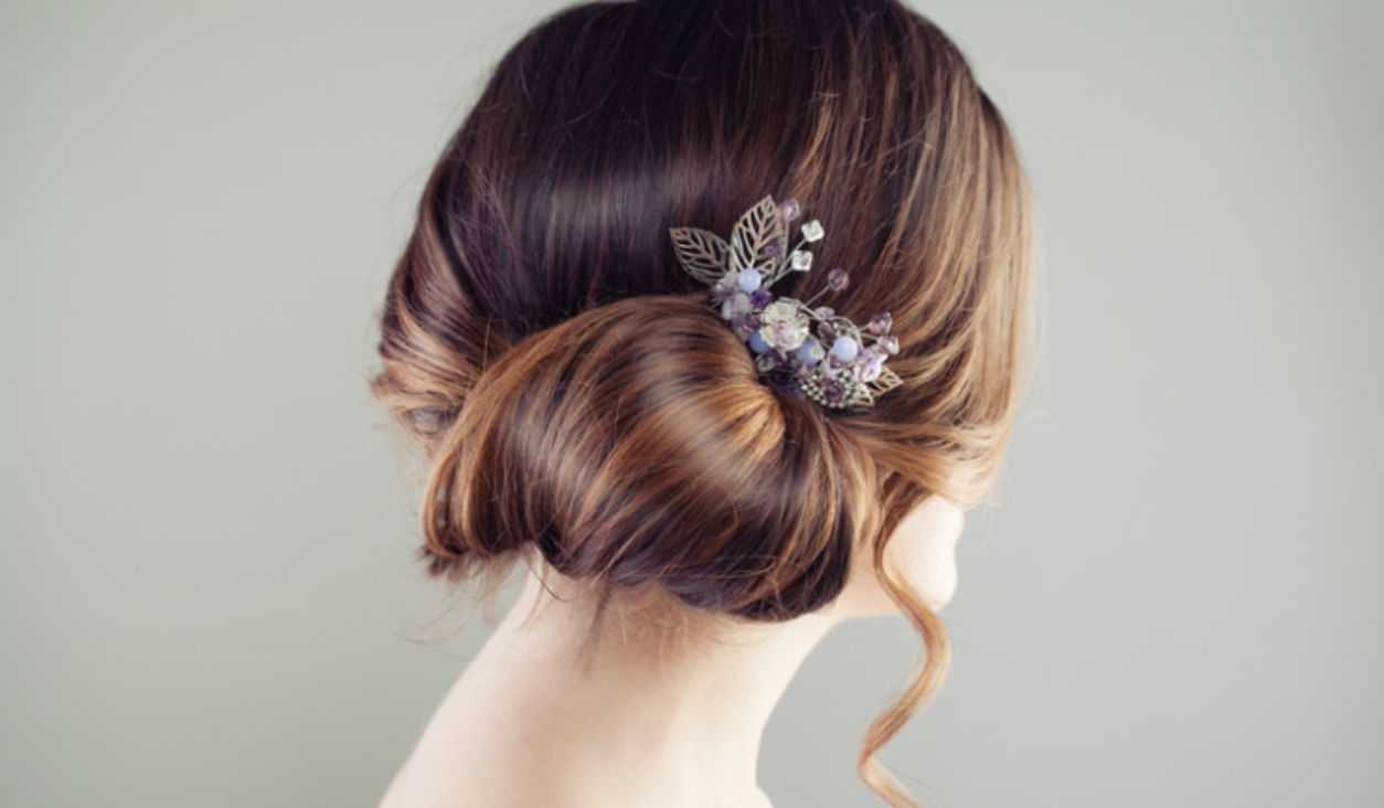 A woman is wearing a bun with a flower in her hair.