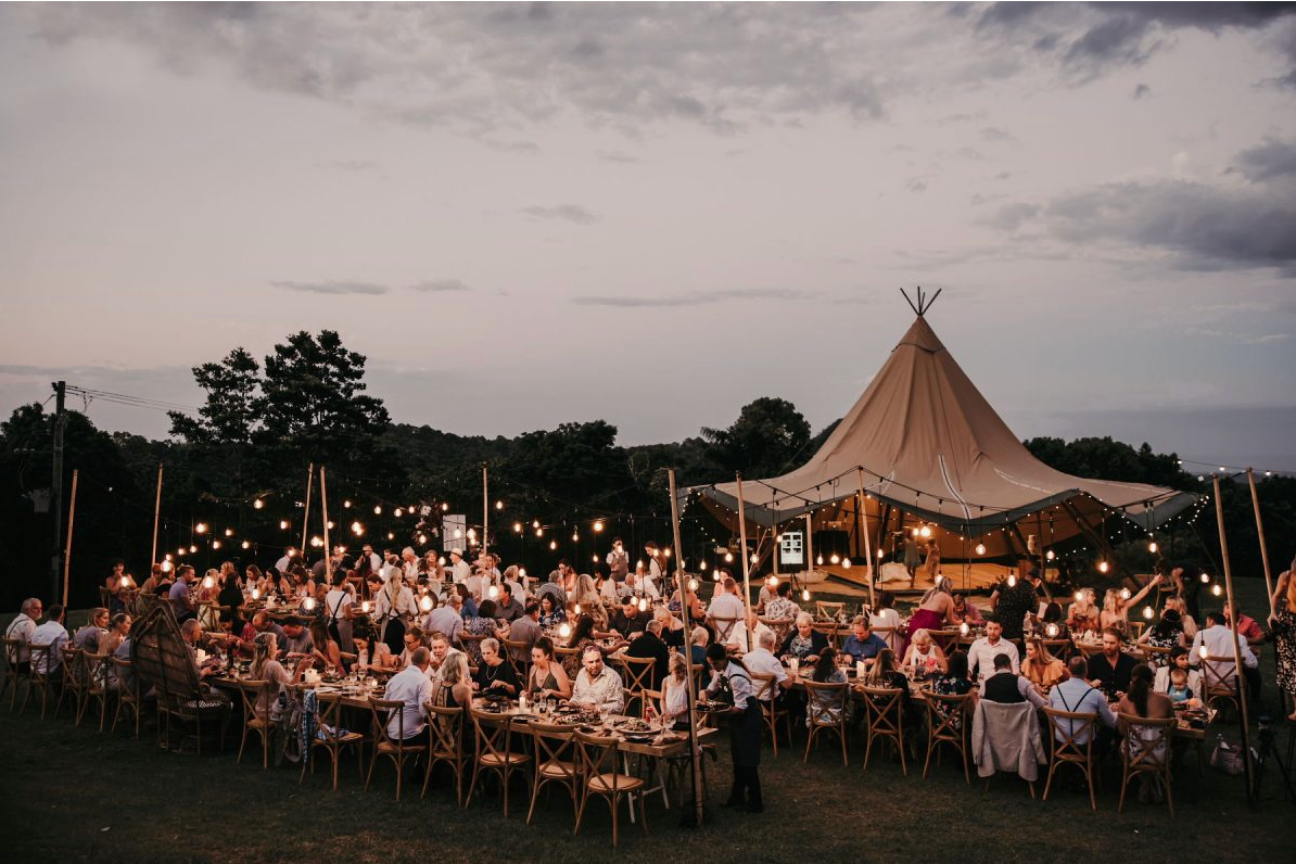 A large group of people are sitting at tables under a tent.