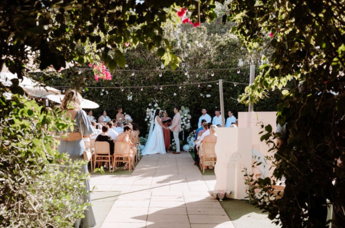 A bride and groom are standing in front of a crowd of people at a wedding ceremony.