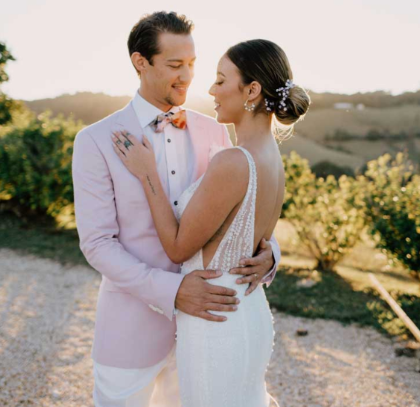 A bride and groom are posing for a picture on their wedding day