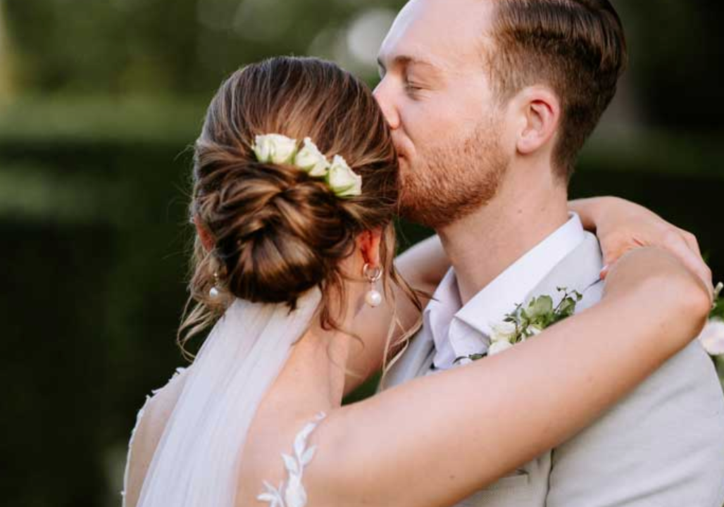 A bride and groom are kissing on their wedding day.