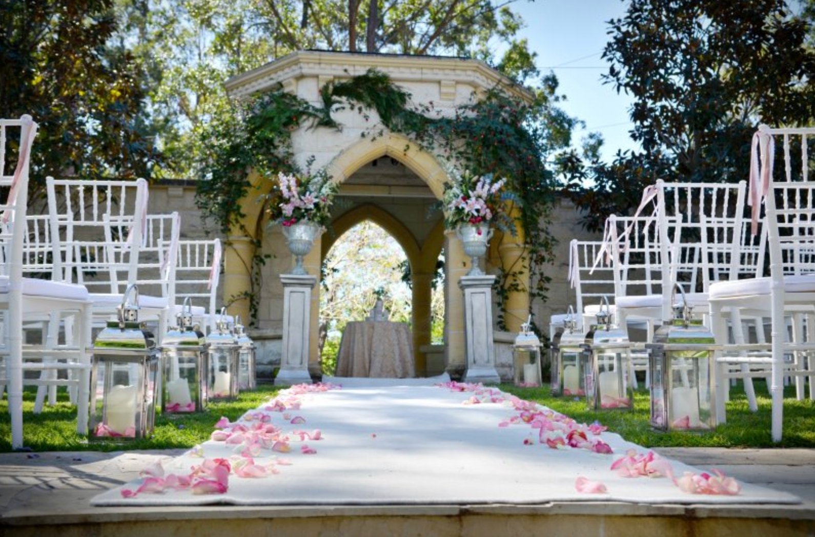 A wedding ceremony is taking place in front of a stone archway.