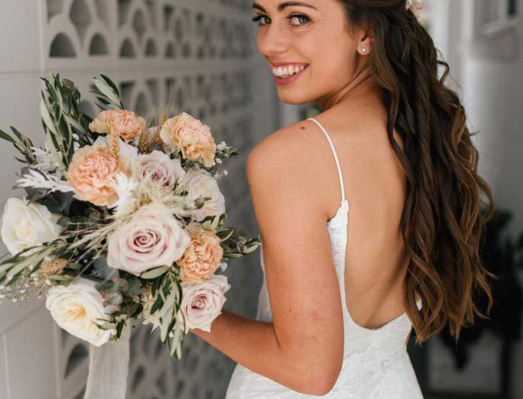 A woman in a white dress is holding a bouquet of flowers.