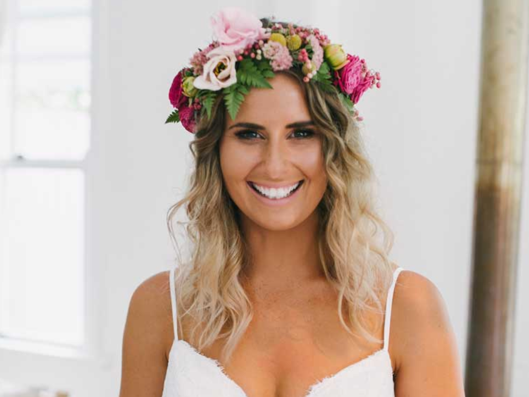 A woman in a white dress is wearing a flower crown on her head.